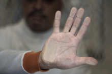 A man with his hand pressed up against glass window. Photo via BRANDON THIBODEAUX FOR HUFFPOST